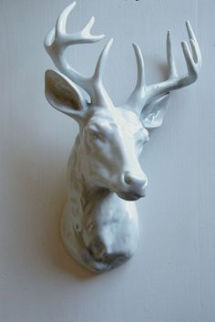 a white deer head mounted to the side of a wall