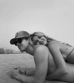 a man and woman laying on top of each other in the sand at the beach