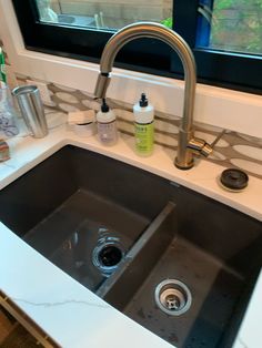 a kitchen sink with two faucets and soap dispensers on the counter