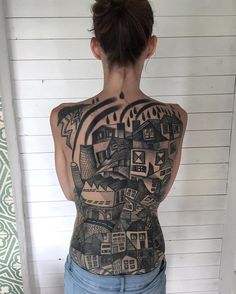 the back of a woman's body is covered in black and grey ink with houses on it