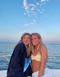 two young women sitting on the back of a boat