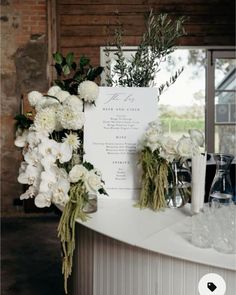 flowers and greenery are arranged on the bar at this rustic wedding reception in an old barn