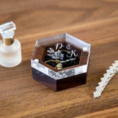 a small wooden box with a wedding ring on it next to a bottle of perfume