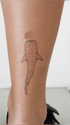 a woman's leg with a tattoo of a whale on it and dots in the shape of a fish