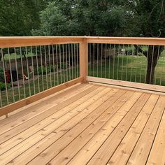 a wooden deck with metal railing and trees in the background