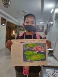 a woman wearing a face mask holding up a sign with water lilies on it