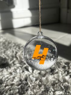 a glass ornament with the letter h hanging from it's side on a carpet