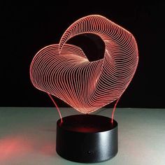 a heart shaped light sitting on top of a wooden stand in front of a black background