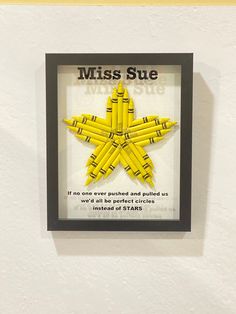 there is a yellow star made out of pencils in a frame on the wall