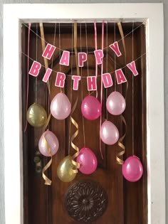 a birthday decoration with balloons and streamers hanging from the front door to spell out happy birthday