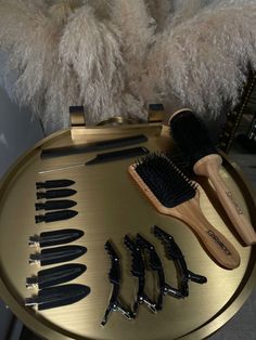 a hairbrush, combs and other items sit on a gold tray next to a fluffy white chair