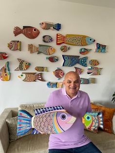 a man sitting on a couch holding a fish shaped pillow in front of his face