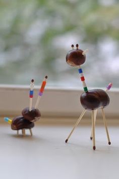 three small wooden sticks with chocolate covered animals on them sitting in front of a window