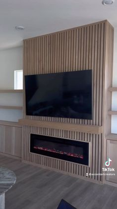 a living room with a large television mounted on the wall and built - in shelving