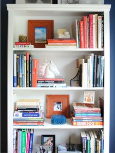 a bookshelf filled with lots of books next to a white horse head statue