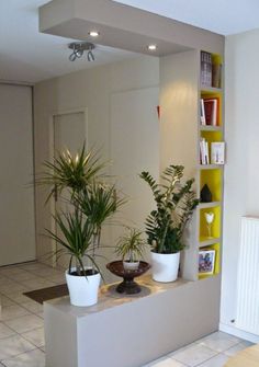 three potted plants sit on a ledge in the middle of a room with white tile flooring