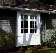 a white window on the side of a gray house