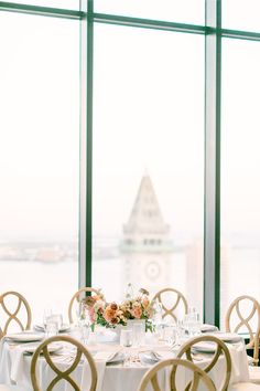 the table is set with white linens, gold chairs and floral centerpieces