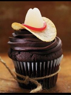 a cupcake with chocolate frosting and a cowboy's hat decoration on top