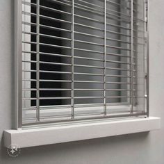 a window with metal bars on it and a white wall in the backround