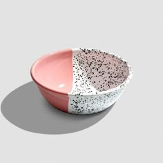 a pink and white bowl with black speckles on the side, sitting in front of a gray background