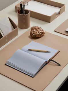 an open notebook and pen sitting on top of a desk next to other office supplies