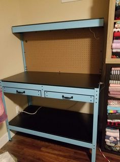 a blue workbench with sewing supplies on it in a room that has wood flooring