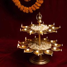 a three tiered tray with candles and rice on the bottom in front of a wreath