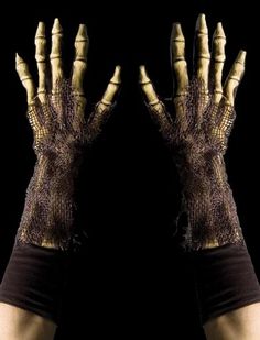 two hands that are covered in fake gold and black gloves with claws on each hand