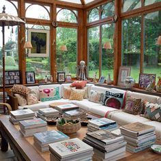 a living room filled with lots of furniture and books on top of a wooden table