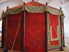 an elaborately decorated red tent in the middle of a room