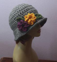 a crocheted hat with flowers on the brim sits on a mannequin head