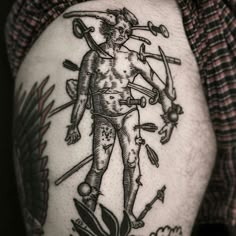 a man with tattoos on his arm holding two swords