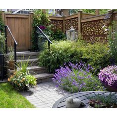 an outdoor garden with flowers and plants in the foreground, next to a wooden fence