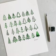 some green trees are drawn on white paper and next to a marker with watercolor pencils