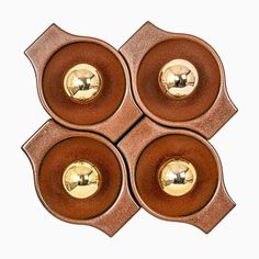 four brown bowls with metal handles and gold knobs on each side, set against a white background