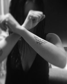 a woman holding her arm with a tattoo on it's left arm and the word wonder written in white ink