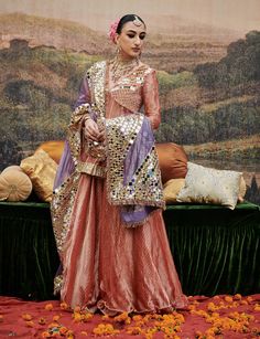 This charming pink tissue sharara set features a peplum-style tunic adorned with intricate zari and mirror work, and a shimmering gota border that exudes traditional elegance. Paired with a lilac dupatta embellished with delicate mirror details, it offers a striking contrast, making this ensemble a perfect blend of contemporary chic and timeless grace for festive celebrations. Tissue Sharara, Peplum Sharara, Kurta Sets For Women Online, Tissue Kurta, Sharara Pants, Peplum Styles, Sharara Set, Contemporary Chic, Indian Ethnic Wear