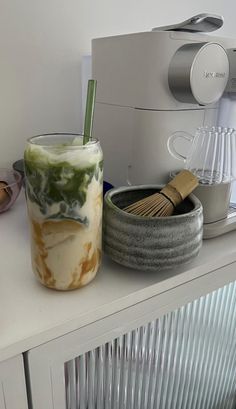 a cup that is sitting on top of a counter next to a bowl and whisk