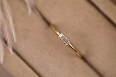 a diamond ring sitting on top of a piece of paper next to a white feather