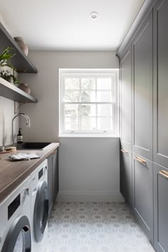 a washer and dryer in a small room with grey cabinets on the walls