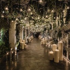 an outdoor event with candles and greenery on the walls, surrounded by white pillar lights