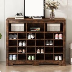 a wooden shelf filled with shoes next to a mirror and vase on top of it