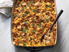 a casserole dish filled with pasta, meat and vegetables on a marble table