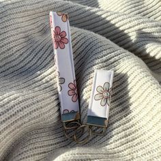 two keychains with flowers on them laying on a blanket