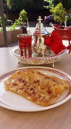 a plate with some food on it next to a cup and saucer in the background