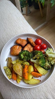 a white plate topped with vegetables and meat on top of a table next to a couch