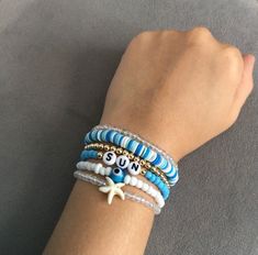 a woman's arm wearing bracelets with beads and charms on it, while she is looking down at her wrist