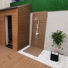 there is a shower in the corner of this backyard with wood flooring and white pebbles