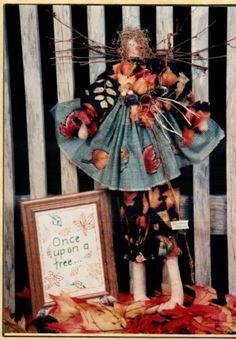 a doll is standing next to a frame with leaves on it and a sign that says, one upon a tree